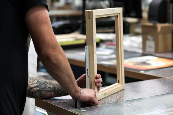 Hand-stretching the canvas over a solid wood stretcher bar in preparation for a Death Metal Uterus canvas print.