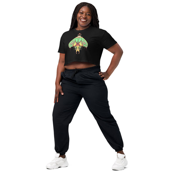 Woman wearing Luna Moth relaxed crop top with hand-drawn green luna moth artwork, paired with black pants and white sneakers.