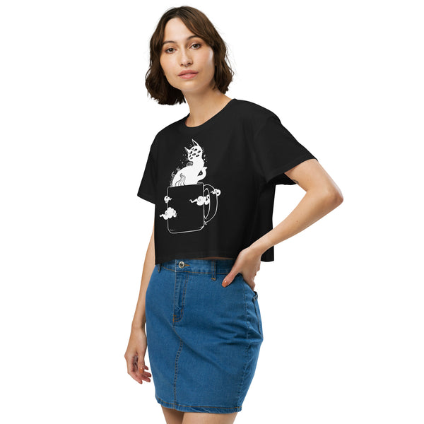 Woman wearing black crop top with creepy cute black cat artwork in coffee cup, styled for gothic or witchy aesthetic.